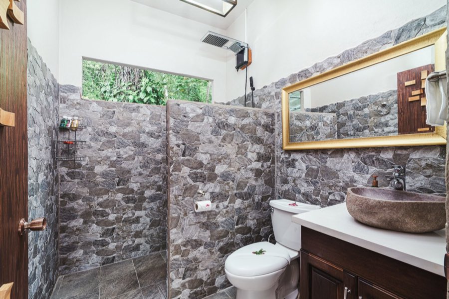 Listing photo of a stone-tiled bathroom with a walk-in shower and vessel sink
