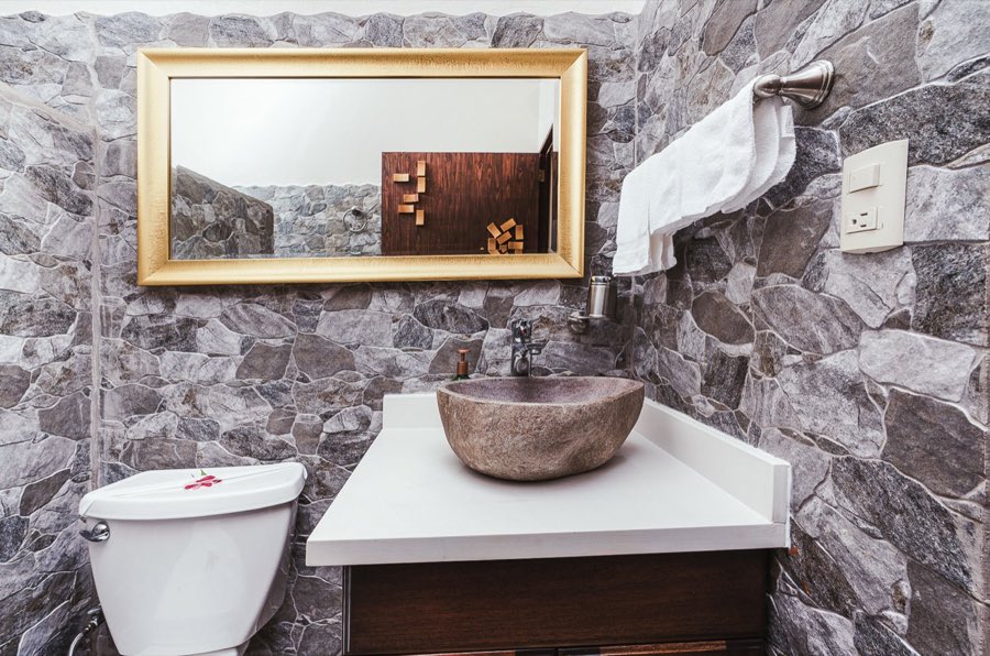 Listing photo of the bathroom vanity with a stone vessel sink and gold-framed mirror