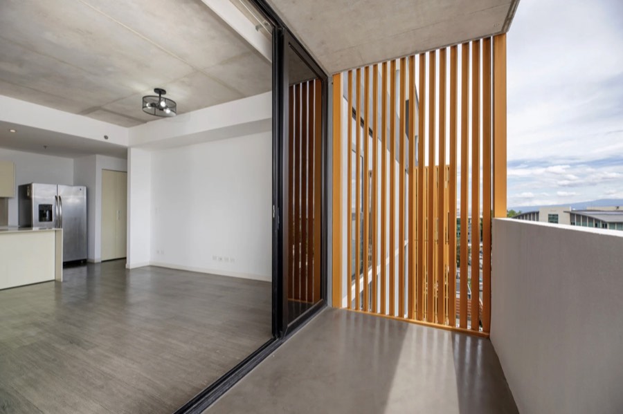 Listing photo of a balcony with orange wood slats and a city view